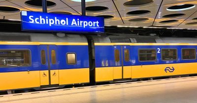 Zug nach Amsterdam Centraal fährt am Bahnsteig am Flughafen Schiphol Amsterdam ab.